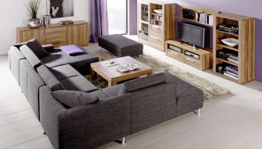 Sofa de esquina modular en color gris oscuro combinado con muebles de madera natural